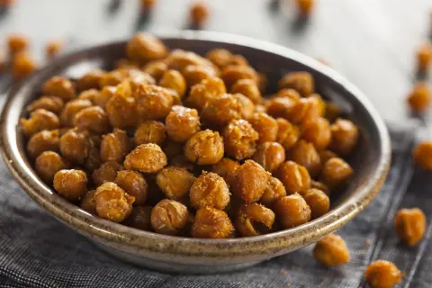 Un tazón lleno de garbanzos fritos dorados y crujientes, perfectos para un aperitivo saludable.