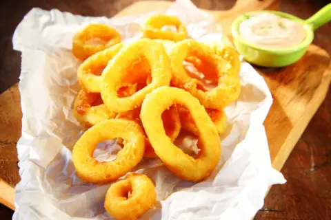 Crujientes calamares a la andaluza, dorados y listos para mojar en una cremosa salsa.