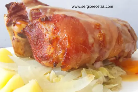 Codillo de cerdo asado, jugoso y dorado, servido con patatas, cebolla y zanahorias. ¡Un manjar!