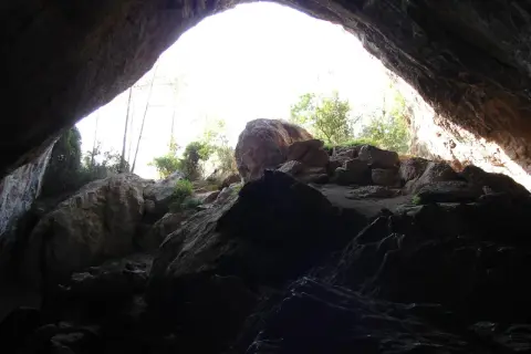 Salida de la cueva negra Montanejos, con rocas y vegetación iluminadas por el sol.