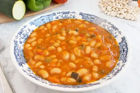 Plato de alubias blancas de bote con verduras en salsa de tomate. Un guiso casero y nutritivo, perfecto para tus recetas.