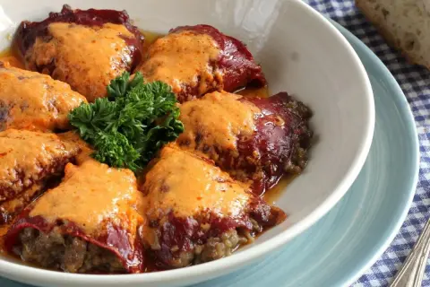 Pimientos rellenos de carne de la abuela, cubiertos con una cremosa salsa y decorados con perejil fresco. Un plato casero que evoca recuerdos.