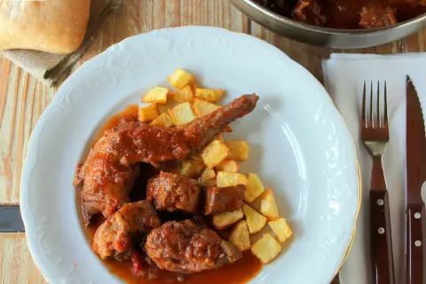 Sabroso conejo guisado en salsa con patatas fritas crujientes. Un plato casero que invita a disfrutar.