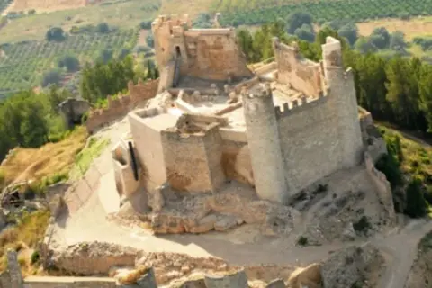 El imponente castillo de Xivert se alza sobre una colina, rodeado de vegetación y campos cultivados. Sus ruinas cuentan historias de batallas y épocas pasadas.