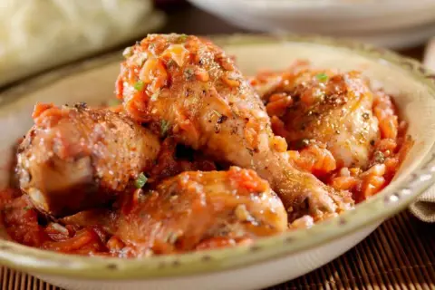 Sabroso pollo guisado en una salsa de tomate con hierbas, servido en un cuenco rústico.
