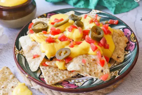 Nachos con queso, cubiertos con jalapeños y tomate picado, listos para disfrutar.