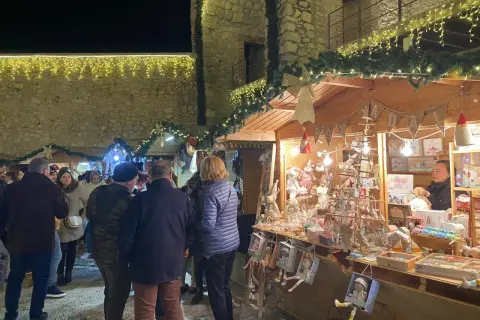 Gente pasea por el mercado navideño Peñíscola, con puestos de adornos y luces festivas.