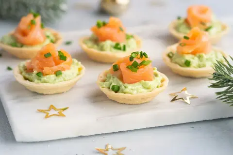 Aperitivos baratos para mucha gente: tartaletas crujientes con aguacate cremoso y salmón ahumado, decoradas con cebollino. ¡Perfectas para fiestas!