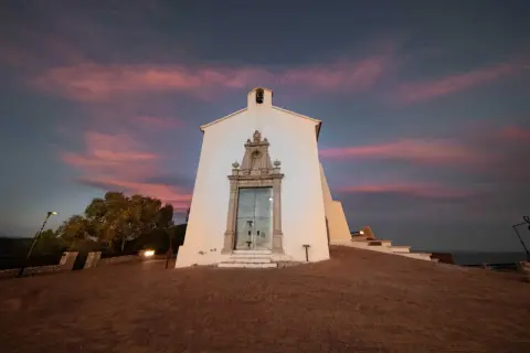 La ermita de Santa Lucía en Alcossebre se alza bajo un cielo crepuscular teñido de rosa y púrpura.