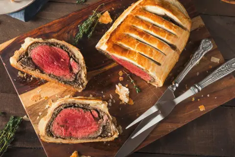 Un delicioso solomillo Wellington, jugoso y envuelto en hojaldre dorado, listo para ser cortado.