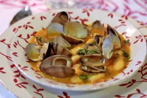 Plato de fabes con almejas, un guiso tradicional con judías blancas tiernas y almejas frescas en una salsa sabrosa.