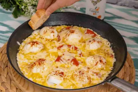 Huevos turcos recién hechos en sartén, con tomate y queso fundido, listos para mojar pan.