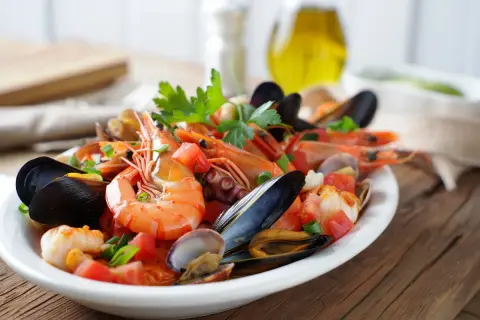 Un delicioso salpicón de marisco con gambas, mejillones, pulpo y almejas, adornado con tomate y perejil.