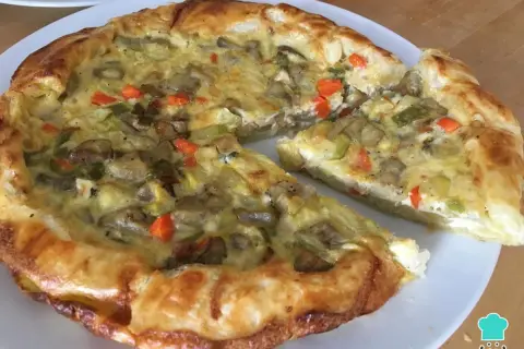 Un delicioso quiche de verduras, con una masa dorada y un relleno cremoso de champiñones, calabacín y zanahoria.