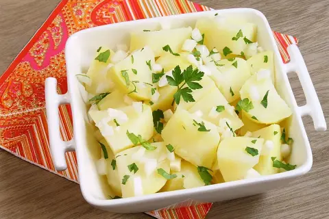 Papas aliñas recién preparadas, con trocitos de cebolla y perejil fresco, listas para disfrutar.