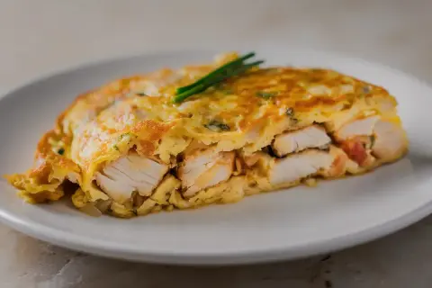Tortilla de bacalao, jugosa y dorada, con trozos de pescado blanco tierno envueltos en huevo.