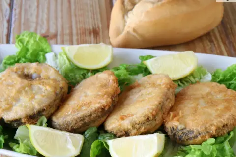 Crujiente merluza a la romana, servida sobre lechuga fresca y gajos de limón. Un plato perfecto para disfrutar.