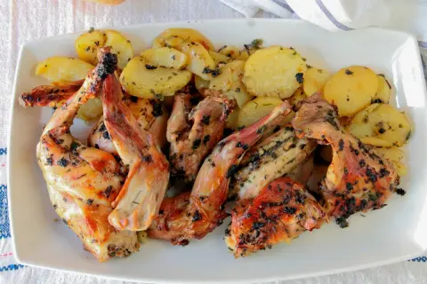 Delicioso conejo al horno con patatas doradas y hierbas aromáticas, listo para servir.