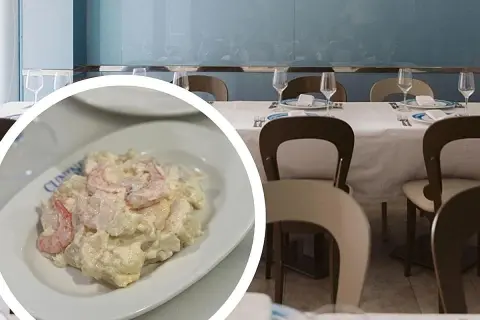 Deliciosa ensaladilla de gambas cremosa, servida en un plato blanco, lista para disfrutar en un restaurante con mesas puestas.