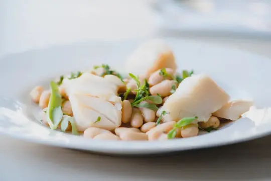 Deliciosa ensalada de bacalao con tiernas judías blancas y hierbas frescas. Un plato ligero y sabroso.