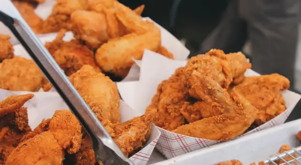 Unas bandejas llenas de crujiente pollo frito, listo para ser servido. Las piezas doradas y sabrosas invitan a disfrutar de este clásico.