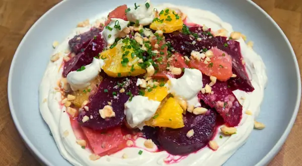 Deliciosa ensalada de remolacha con cítricos, crema y frutos secos picados.