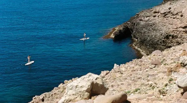 Dos personas hacen paddle surf en aguas turquesas, una actividad genial que ver en Alcossebre con niños.
