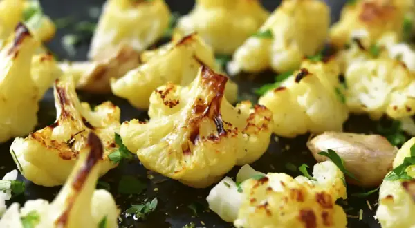 Coliflor al ajillo, dorada y tierna, con trozos de ajo y perejil fresco espolvoreado. Un plato sencillo y delicioso.