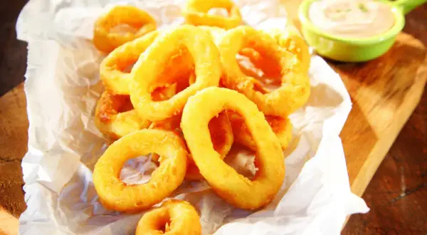 Crujientes calamares a la andaluza, dorados y listos para mojar en una cremosa salsa.
