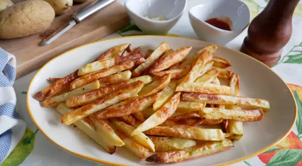 Patatas fritas doradas y crujientes, recién salidas de la freidora de aire. Perfectas para acompañar cualquier comida.