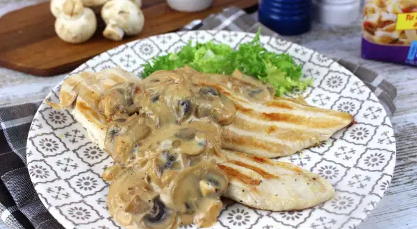 Sabroso pollo con champiñones en salsa cremosa, servido con lechuga fresca en un plato decorado.