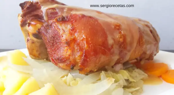 Codillo de cerdo asado, jugoso y dorado, servido con patatas, cebolla y zanahorias. ¡Un manjar!