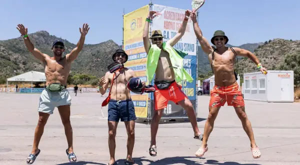 Cuatro amigos saltan de alegría frente a un cartel del FIB Benicàssim. ¡La fiesta está a punto de empezar!