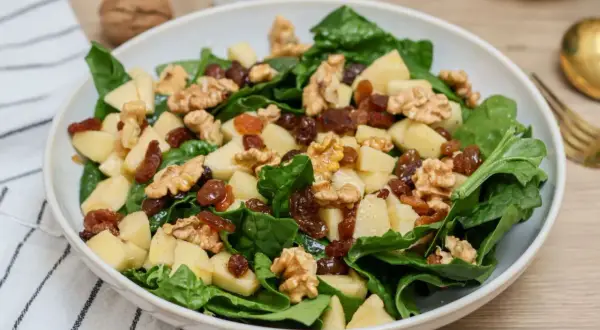 Deliciosa ensalada de espinacas con trozos de manzana, pasas y nueces crujientes. Un festín de texturas y sabores.