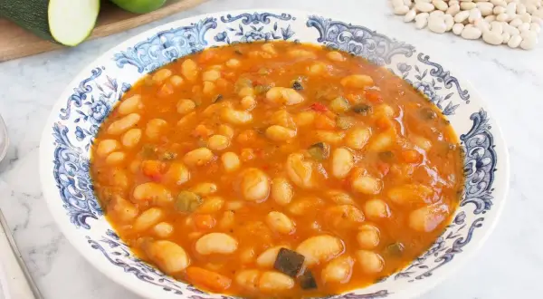 Plato de alubias blancas de bote con verduras en salsa de tomate. Un guiso casero y nutritivo, perfecto para tus recetas.