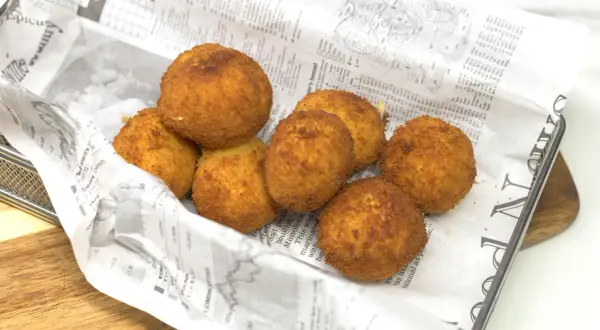 Croquetas de gambas doradas y crujientes, servidas en una bandeja con papel de periódico.