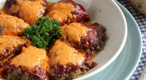 Pimientos rellenos de carne de la abuela, cubiertos con una cremosa salsa y decorados con perejil fresco. Un plato casero que evoca recuerdos.