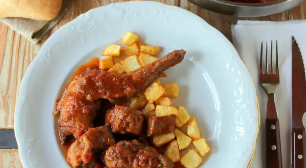 Sabroso conejo guisado en salsa con patatas fritas crujientes. Un plato casero que invita a disfrutar.