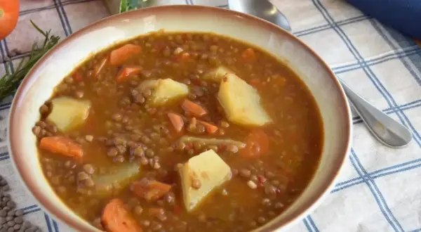 Un tazón humeante de lentejas estofadas Arguiñano, con patatas y zanahorias, listo para disfrutar.