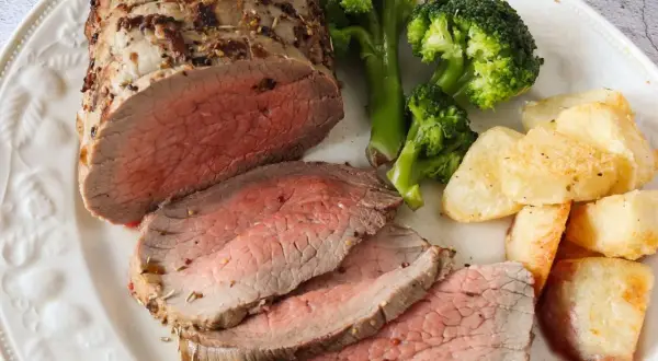 Jugoso roast beef cortado en rodajas, acompañado de brócoli al vapor y patatas asadas crujientes. Un festín para los sentidos.