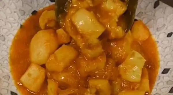 Un plato de papas con choco en una salsa naranja.