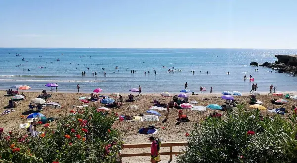 Playa llena de gente disfrutando del sol y el mar. ¡Un día perfecto para saber qué hacer en Alcossebre!