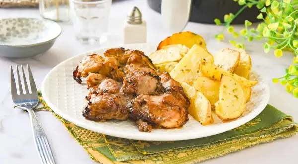 Jugosos contramuslos de pollo dorados con patatas asadas, un plato perfecto para disfrutar.