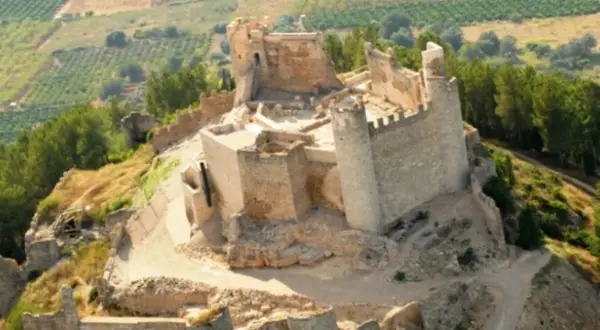 El imponente castillo de Xivert se alza sobre una colina, rodeado de vegetación y campos cultivados. Sus ruinas cuentan historias de batallas y épocas pasadas.