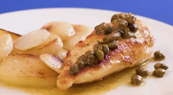 Pechuga de pollo dorada con alcaparras, servida con patatas salteadas en una salsa dorada.
