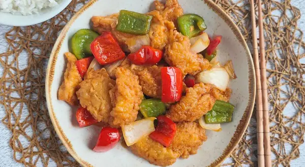 Saborea este delicioso pollo agridulce, crujiente por fuera y tierno por dentro, con pimientos y cebolla. ¡Un festín para tus sentidos!