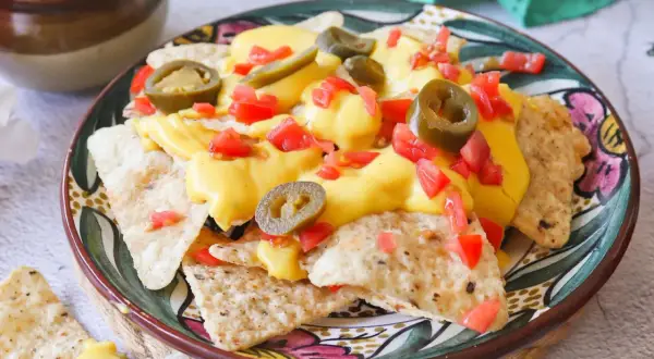 Nachos con queso, cubiertos con jalapeños y tomate picado, listos para disfrutar.
