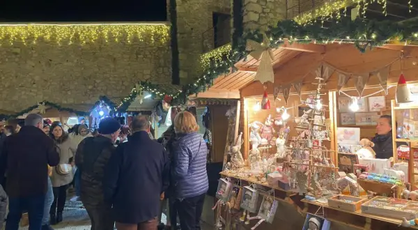 Gente pasea por el mercado navideño Peñíscola, con puestos de adornos y luces festivas.