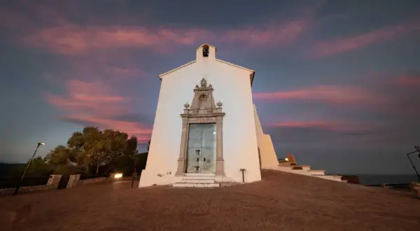 La ermita de Santa Lucía en Alcossebre se alza bajo un cielo crepuscular teñido de rosa y púrpura.