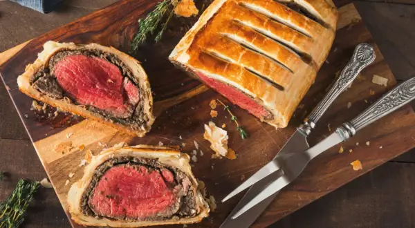 Un delicioso solomillo Wellington, jugoso y envuelto en hojaldre dorado, listo para ser cortado.